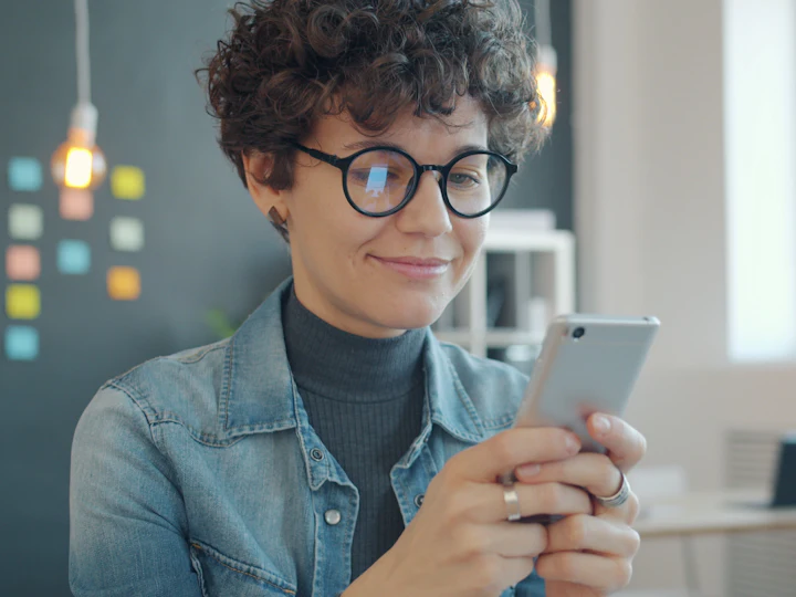 A smiling woman looking at a photo on her phone